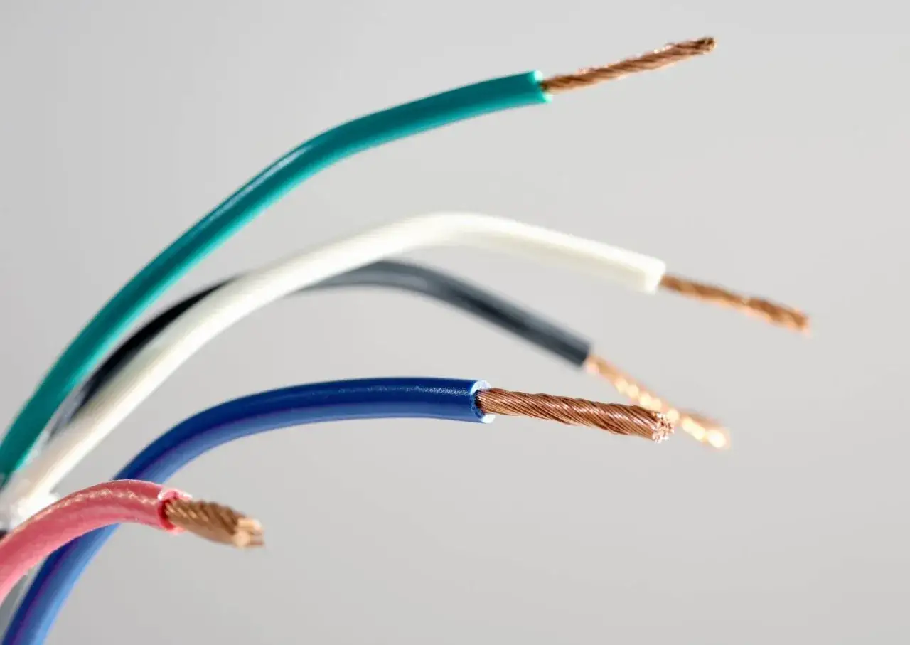 Kolorowe oznaczenia przewodów elektrycznych: zielony, biały, czarny, niebieski i różowy, z odsłoniętymi miedzianymi żyłami.